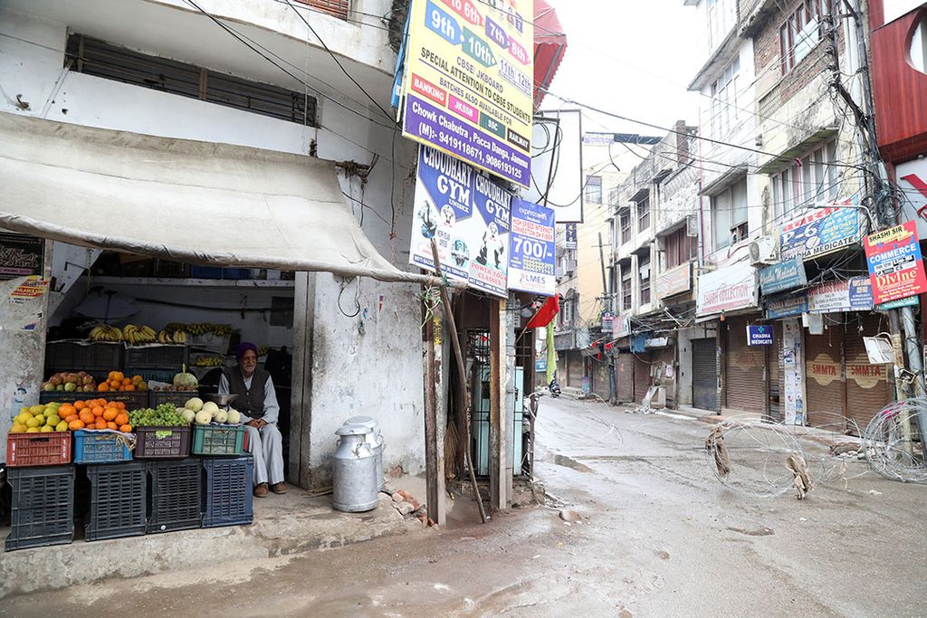 Een fruitverkoper wacht op klanten in zijn shop. De prijzen in India kelderen en het transportsysteem ligt na veertig dagen van lockdown in duigen. Foto: ANP