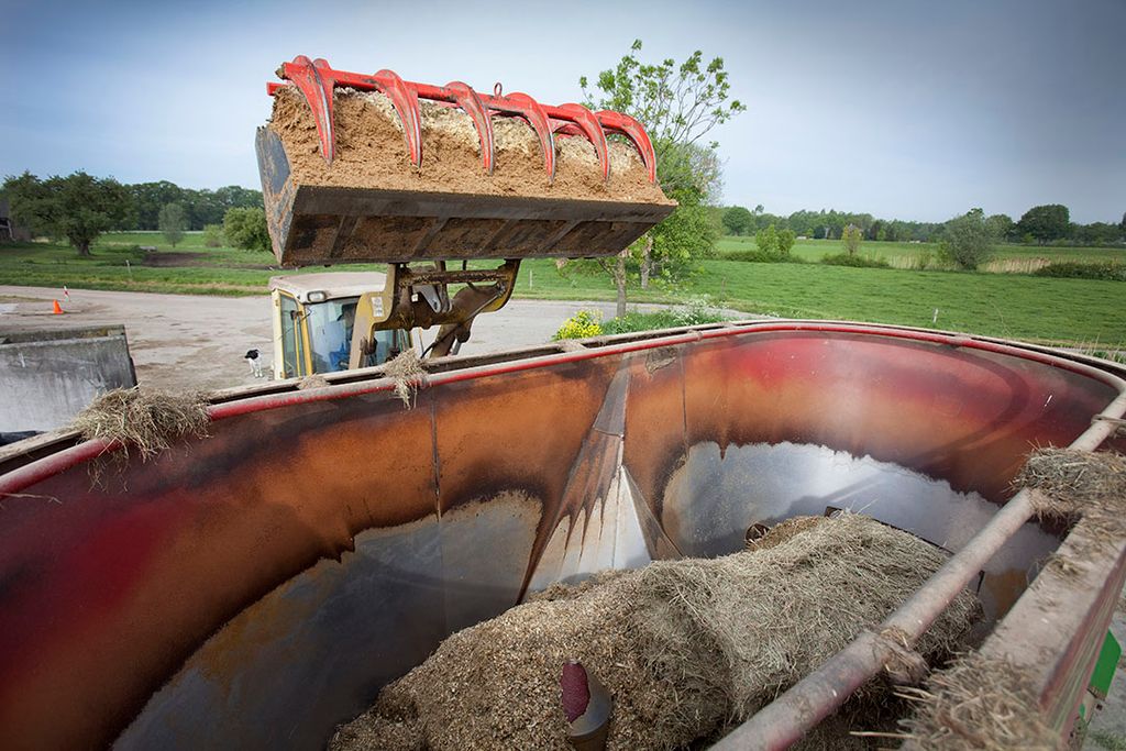 Een shovel schept vochtrijk mengvoer, waaronder bierbostel, in een voermengwagen. - Foto: Jan Willem Schouten