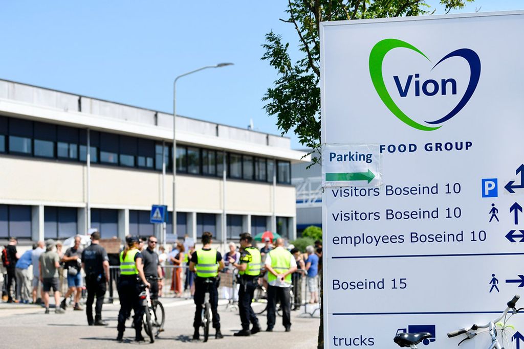 Demonstranten bij slachterij Vion in Boxtel (N.-Br.) vrijdagmiddag 26 juni. De politie houdt een oogje in het zeil. - Foto: ANP