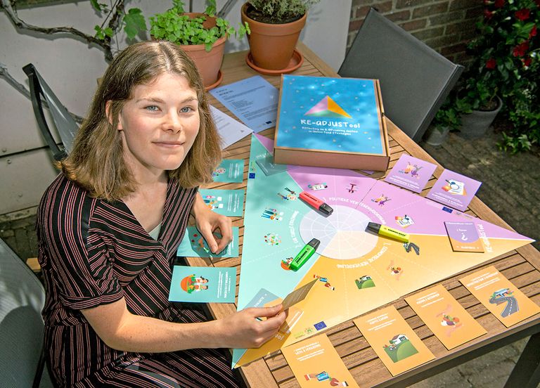 Sara Smaal met de door haar ontwikkelde RE-ADJUSTool. “Met dit spel kunnen beleidsmakers, stakeholders en burgers in discussie gaan over wat belangrijk is voor hen in een voedselstrategie." - Foto: Cor Salverius Fotografie