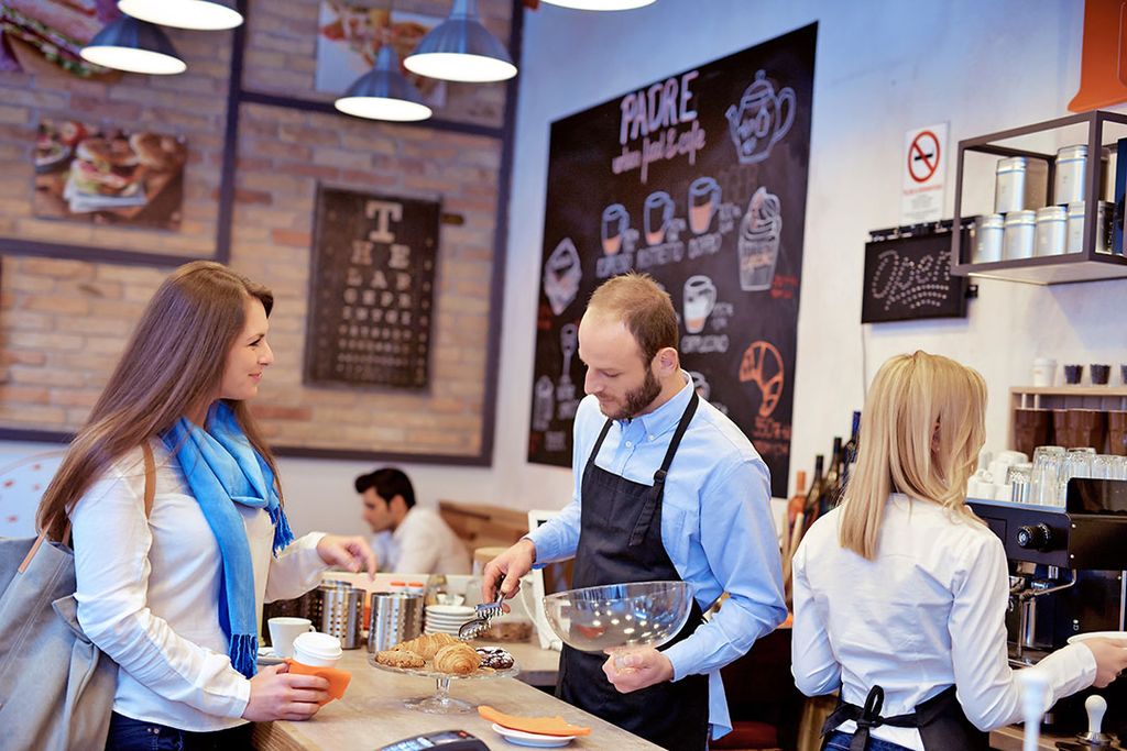 Een vrouw wordt geholpen in een koffiebar. Vorig jaar verliep het in de horeca wat beter dan in rampjaar 2020. - Foto: Canva/StockLite