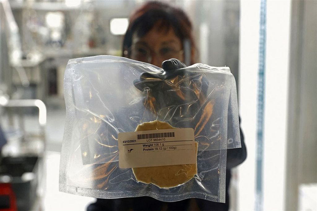 Een medewerker van SuperMeat toont gekweekt kippenvlees. - Foto: AFP