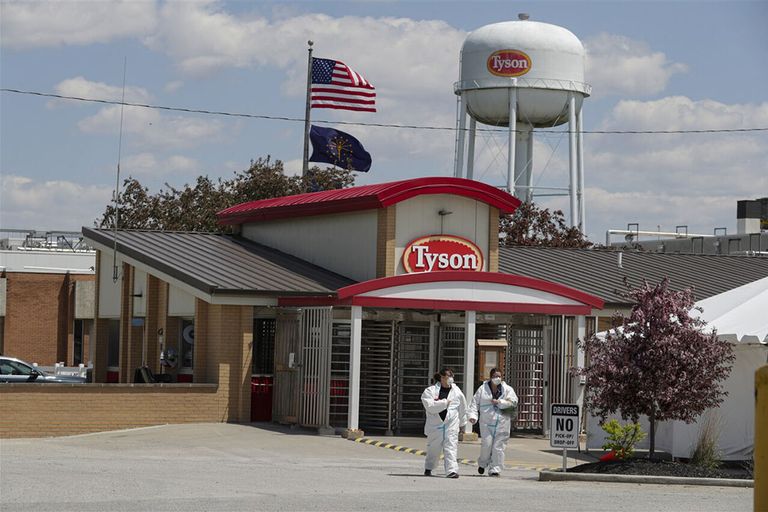Twee medewerkers van Tyson Foods verlaten een locatie van de slachterij in de Verenigde Staten. - Foto: ANP