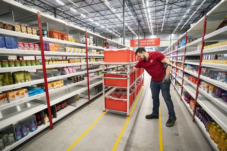 Een medewerker verzamelt producten in de schappen van het distributiecentrum van de online supermarkt Picnic. - Foto: ANP