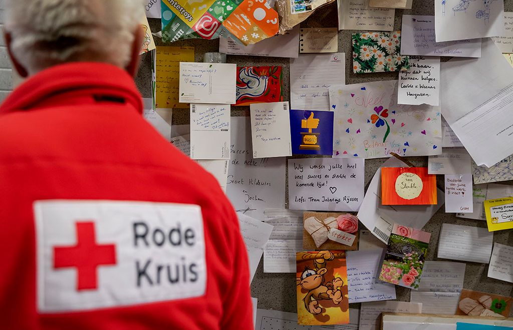 Een vrijwilliger van het Rode Kruis bij een wand met kaartjes die in de dozen met materiaal die ze toegezonden krijgen zaten. - Foto: ANP