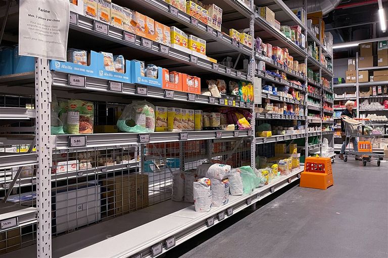 Lege schappen waar normaal meel staat in een Colruyt-winkel in Brussel. Er is een tekort aan grondstoffen en productiekosten zijn gestegen. - Foto: ANP