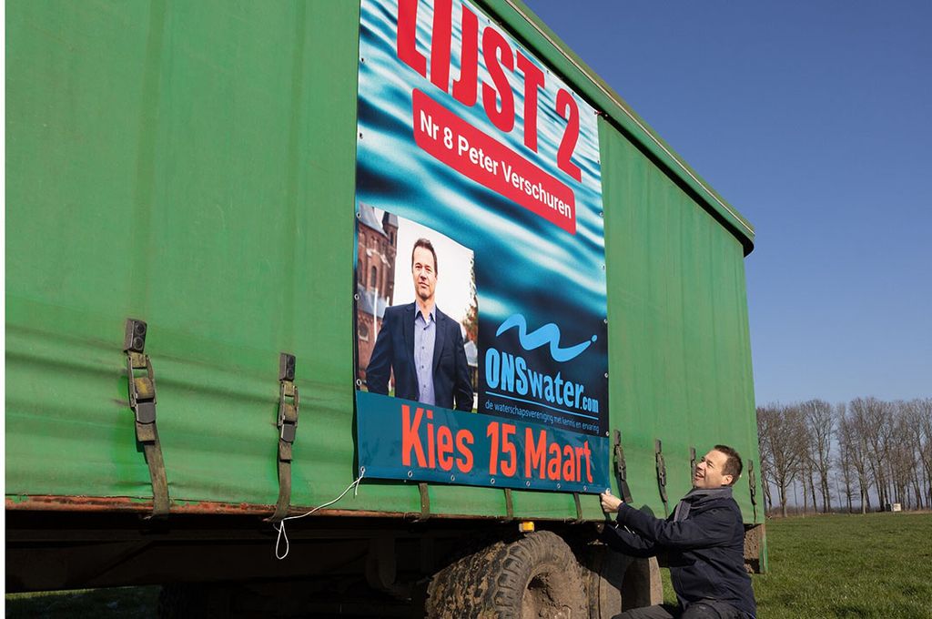 Groenteteler Peter Verschuren (50) kandidaat voor de waterschapsverkiezingen bij zijn spandoek op een oogstwagen op zijn bedrijf in Raamsdonk. - Foto: Misset